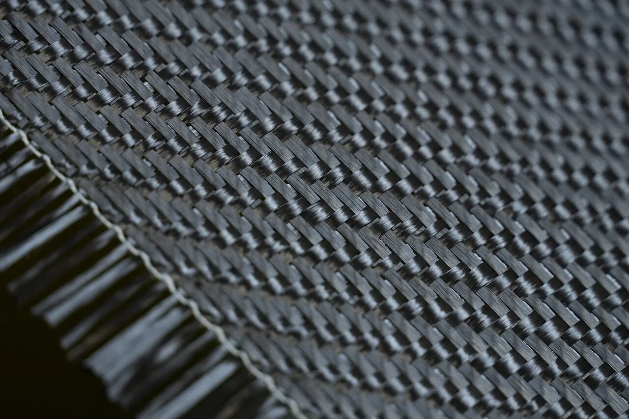 Close-up of black woven carbon fibre fabric, showing the criss-cross pattern of the fibre bundles
