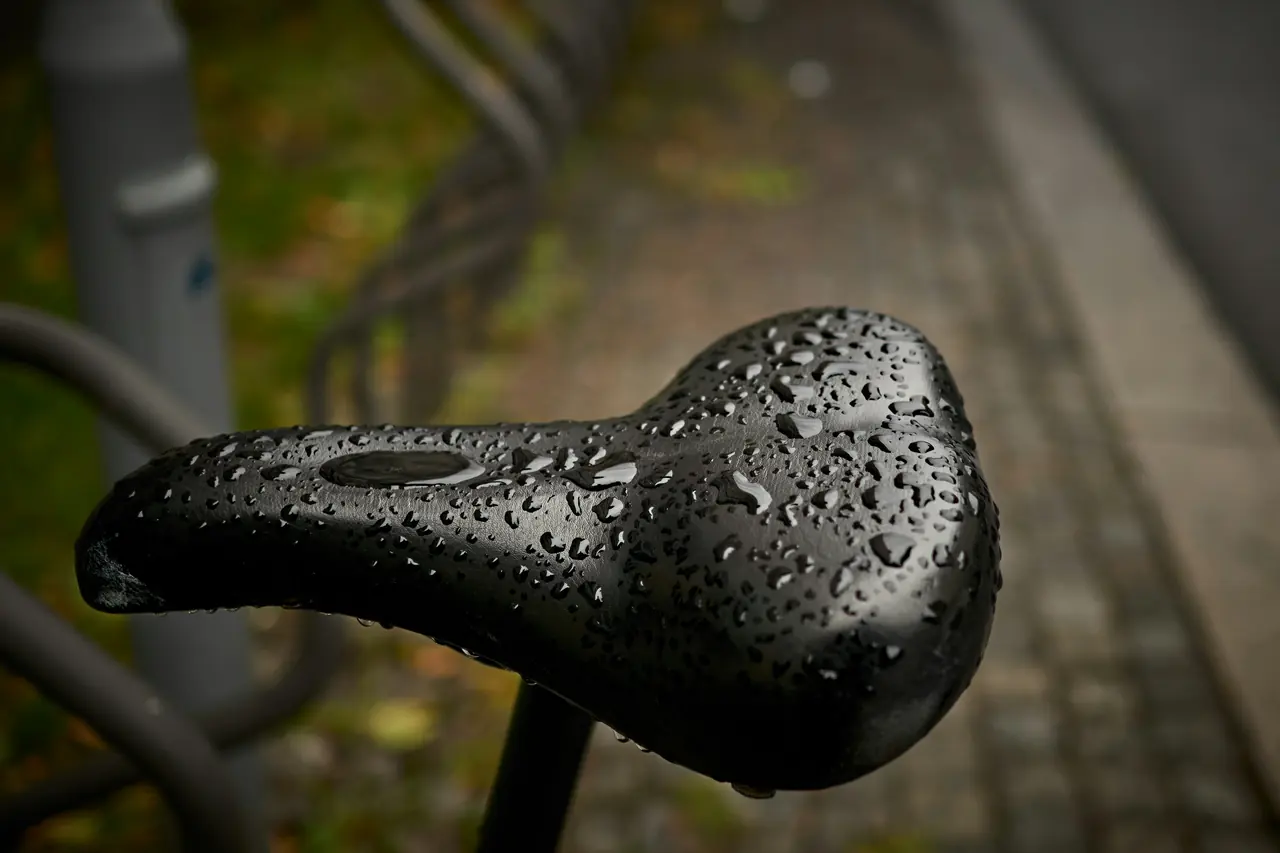 Black bicycle saddle covered in raindrops